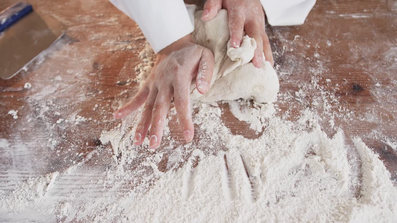 베이커리 부 ⁇ 에서 일하는 아시아 여성 베이커, 느린 동작으로 카운터에 반죽을  ⁇ 는