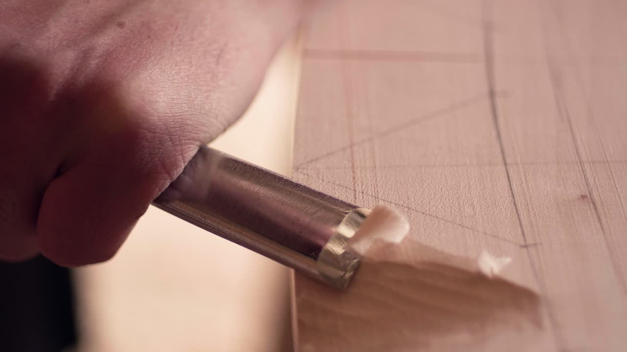 Treskjæringsprosess der en metallmeisel fjerner trefibre for å forme materialets overflate. Nærbilde i sakte film.