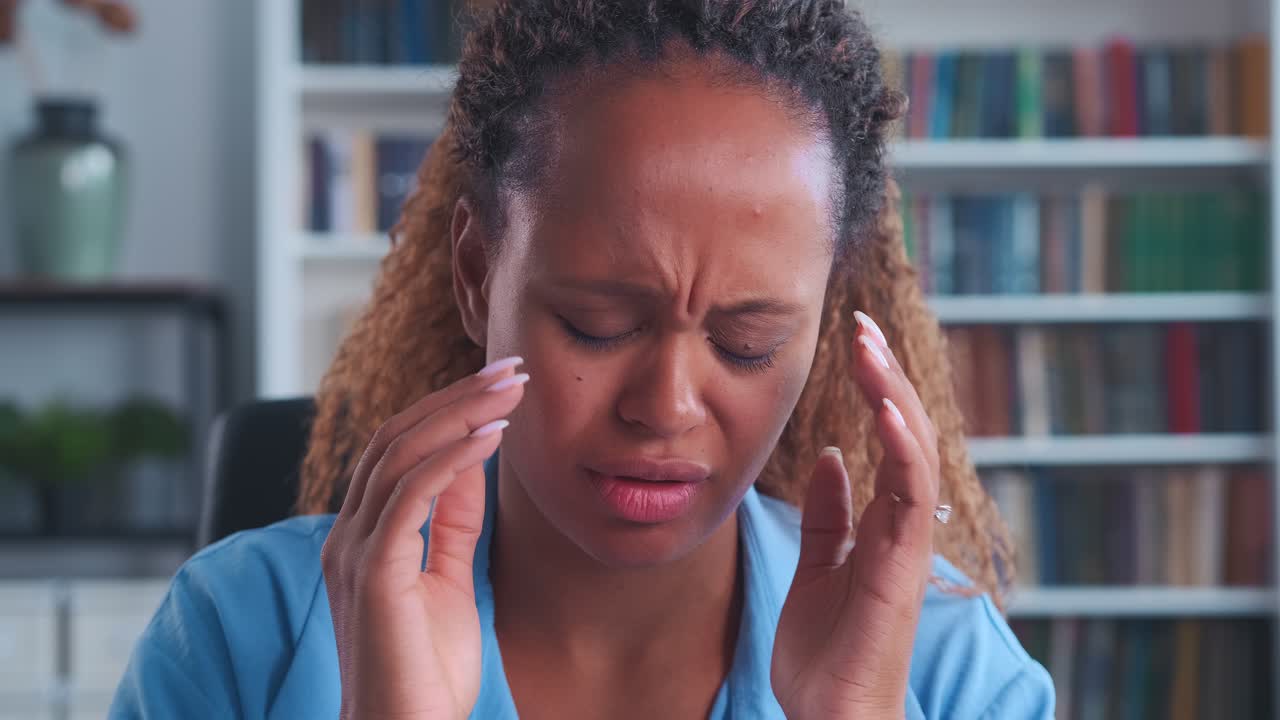 joven mujer afroamericana enferma agarrando los templos sufriendo de migraña