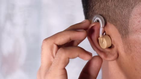 person adjusting hearing aid