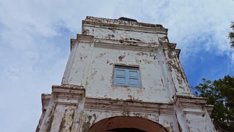 rustic ruins of the historical church of saint paul in malacca, malaysia under the bright cloudy sky - tilt down pan shot