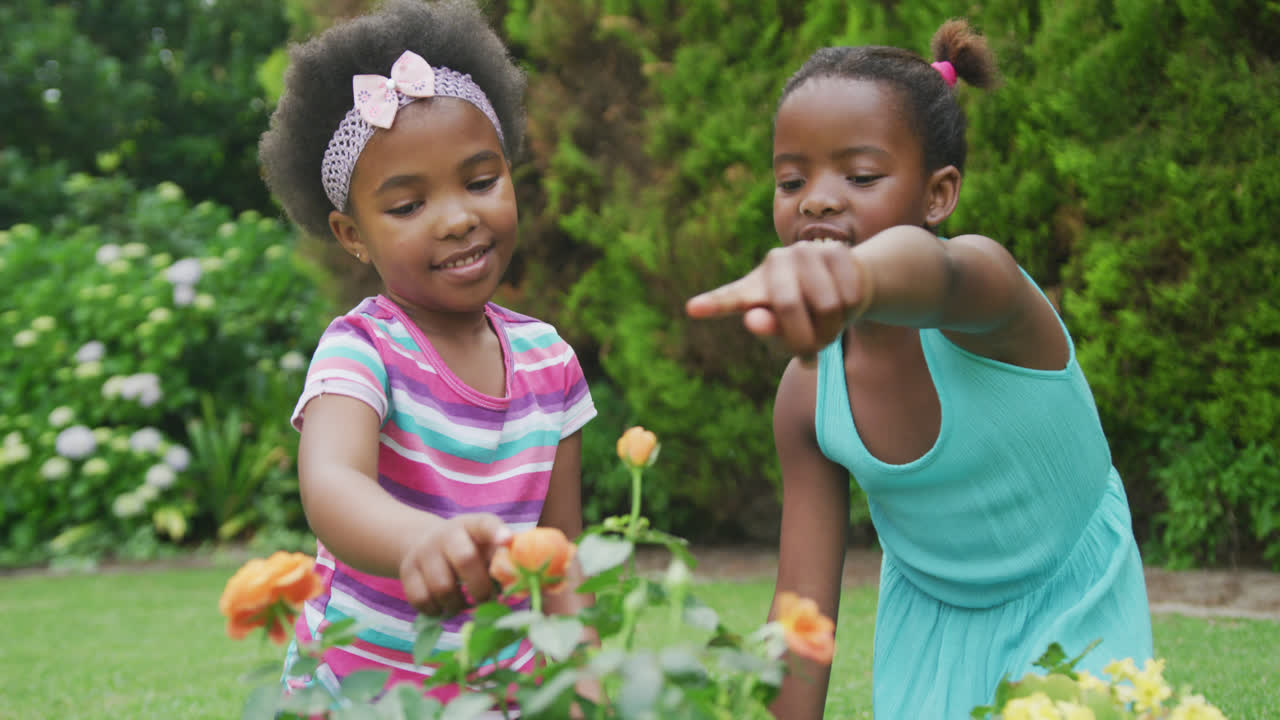 niñas afroamericanas felices regando plantas y trabajando en el jardín