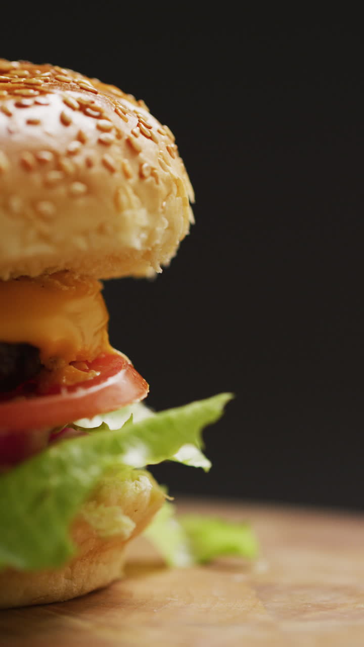 video vertical de primer plano de una hamburguesa casera fresca con ensalada en fondo gris