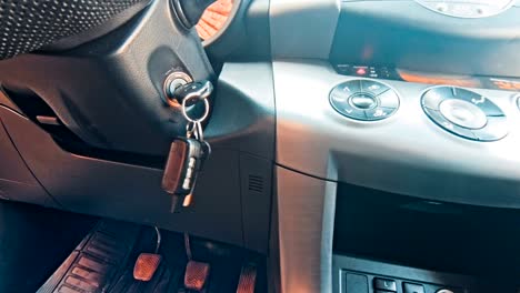 person hand inserting key to start car