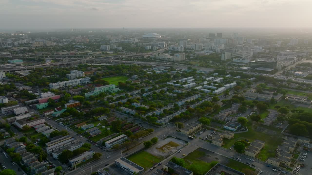 도시 위 를 뒤로 날아다니며 나무 와 초록색 으로 둘러싸인 건물 들 이 있다. 황혼 에 있는 이웃 의 공중 전망
