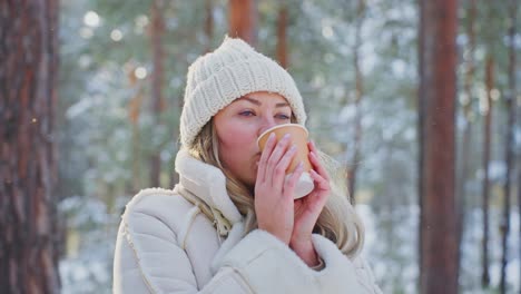 woman enjoying a warm drink in a snowy forest