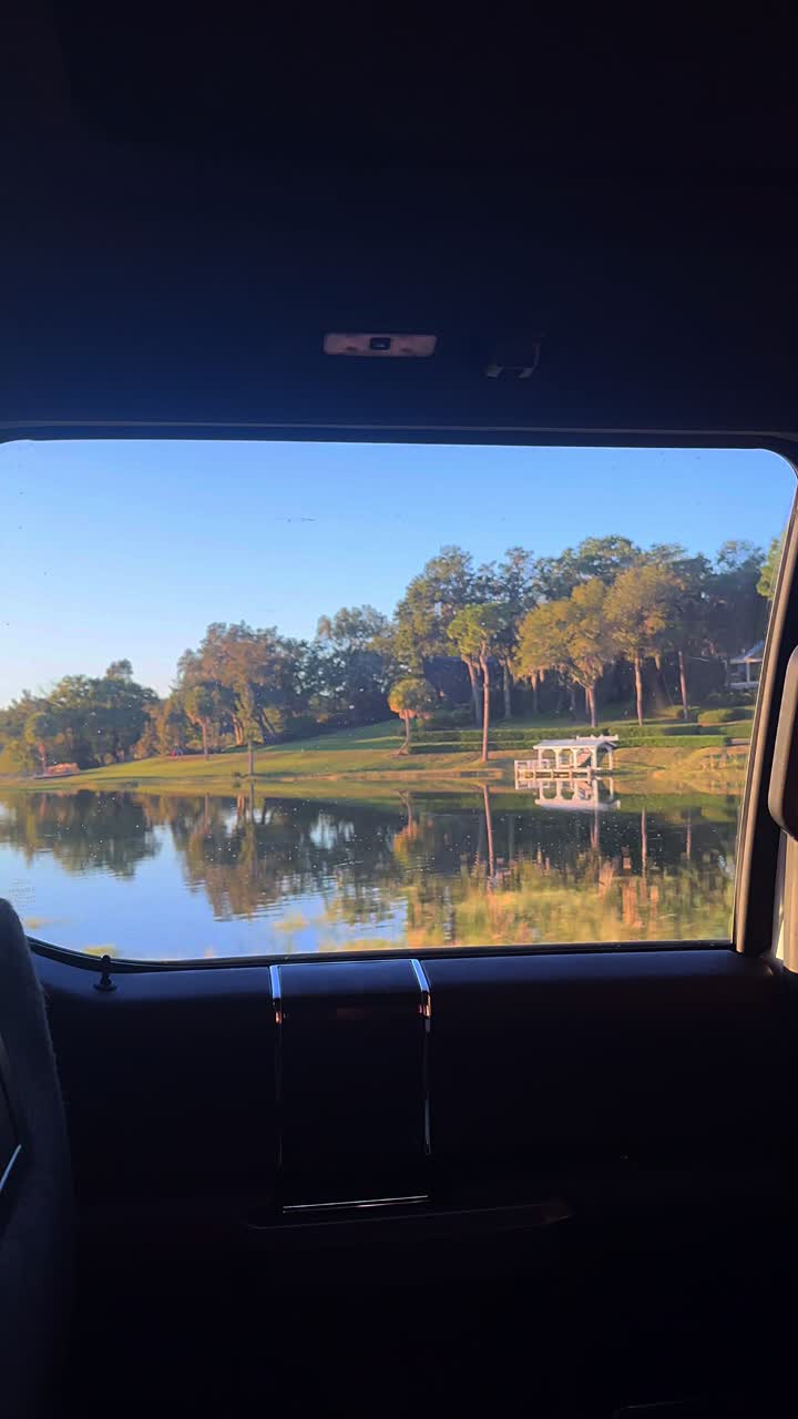 vista del amanecer y el atardecer desde una ventana de coche en un campo de golf cerca de un lago