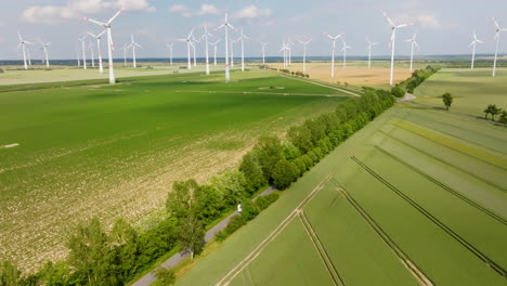 aerial view circling a motorhome driving in middle of wind turbines, summer day