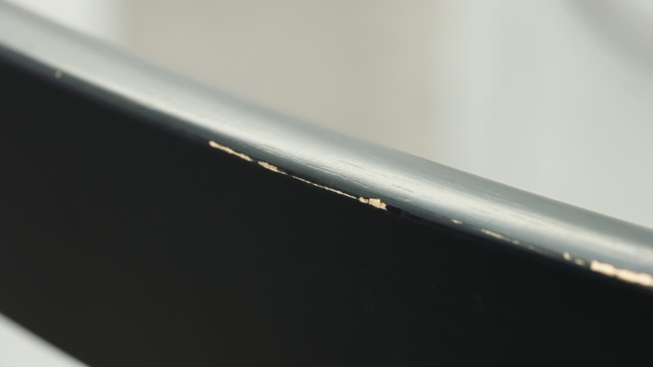 Still close up shows mid-panel wear on dining chair back, exposing wood