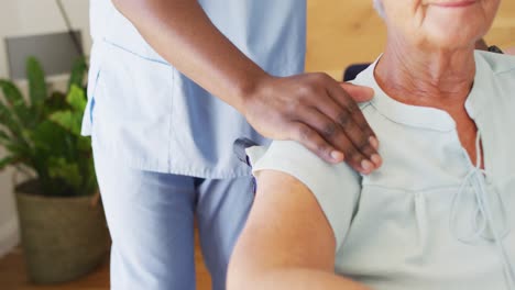 Video-of-hands-of-african-american-male-doctor-supporting-caucasian-senior-woman