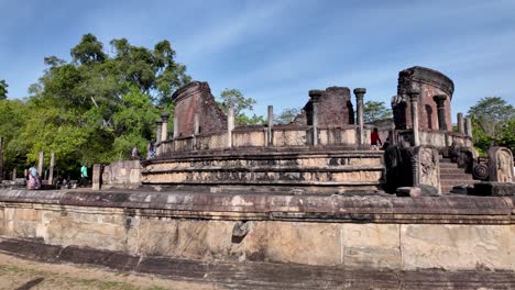 tourists admire the historic architecture of polonnaruwa vatadage, a cherished relic from sri lanka's ancient kingdom of polonnaruwa, pan right shot