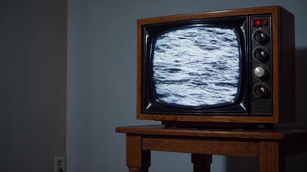 Vintage TV on a wooden stand displaying static, captured from a side angle