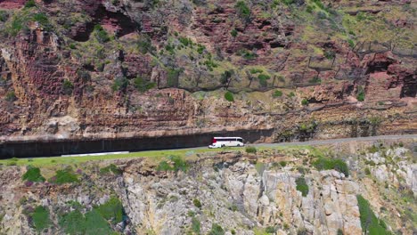 Una-Toma-Aérea-De-Un-Automóvil-Que-Viajaba-Por-Una-Peligrosa-Y-Estrecha-Carretera-De-Montaña-A-Lo-Largo-Del-Océano-Chapmans-Peak-Road,-Cerca-De-Ciudad-Del-Cabo,-Sudáfrica-1