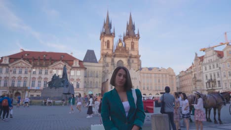 woman stand on busy tourism street of prague, church tower in background