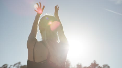 Vista-Trasera-En-Cámara-Lenta-De-Una-Mujer-Rubia-Haciendo-Yoga-Afuera-Bajo-La-Luz-Del-Sol