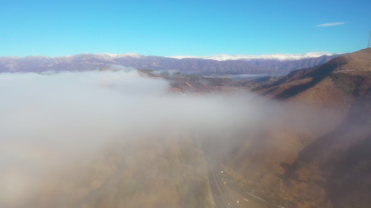 la antena sobre las nubes y la niebla revela el valle de ojai y las montañas topatopa cubiertas de nieve en invierno