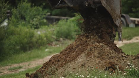 Cucharón-De-Excavadora-Descargando-Una-Carga-Fresca-De-Suciedad-Del-Suelo-Tiro-Detallado