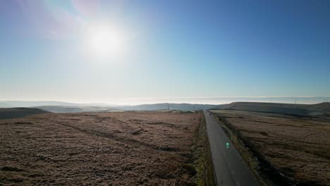 Autos,-Die-Eine-Landstraße-Hinunterfahren,-Während-Die-Sonne-Tief-Am-Himmel-Steht-Und-Blendenflecke-Zeigt