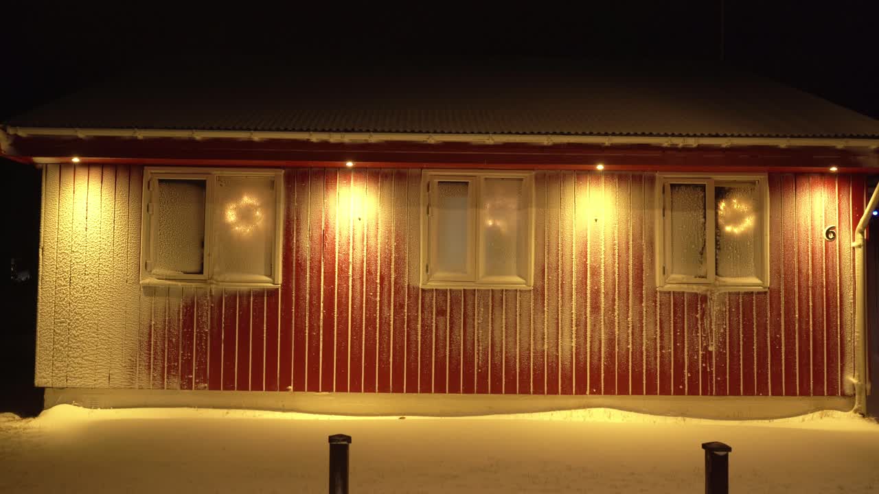 Mysterious shot in the evening of a cozy house with windows and walls covered with blowing snow.