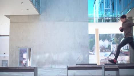 a young parkour athlete jumping from one bench to another one in a modern environment in 4k