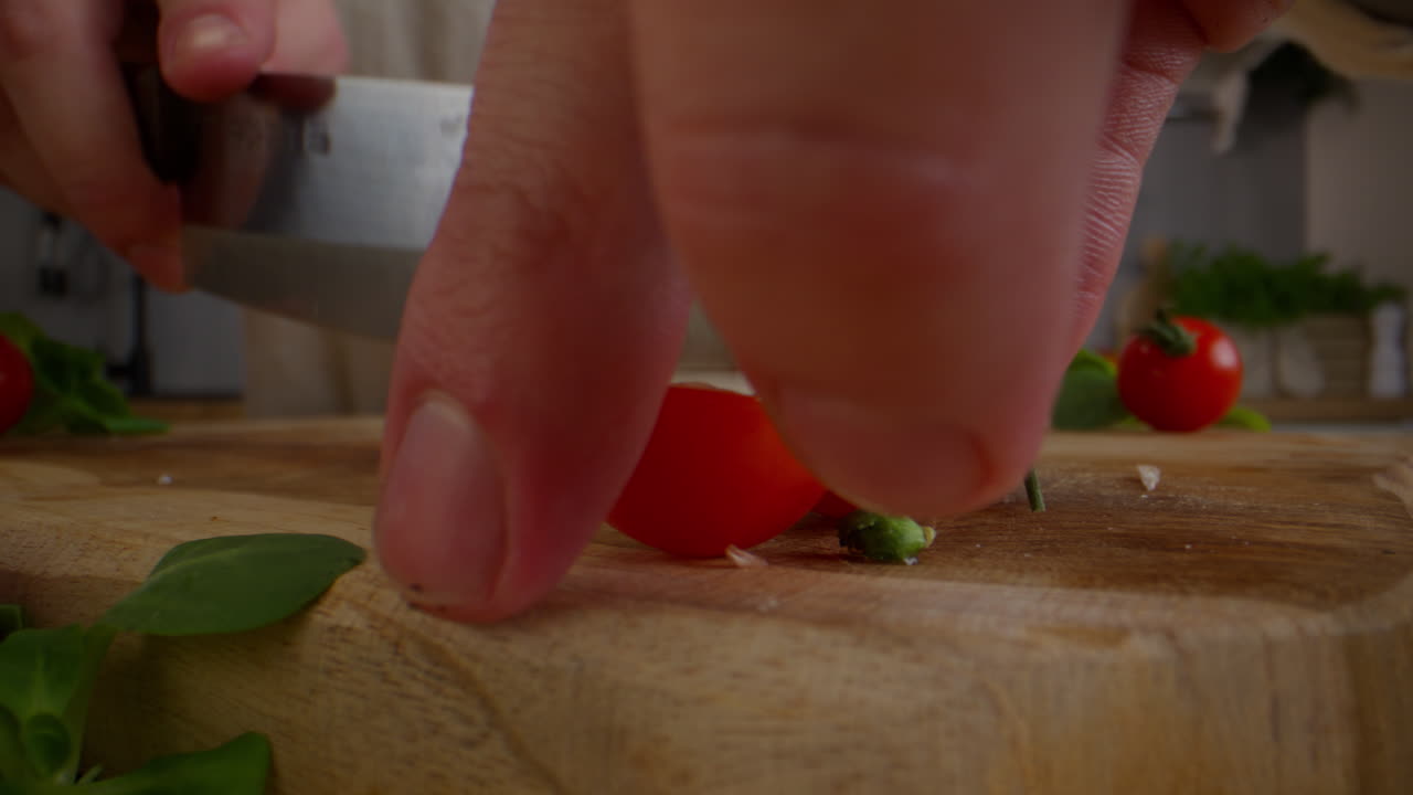 셰프가 체리 토마토를 잘라내고 있습니다.