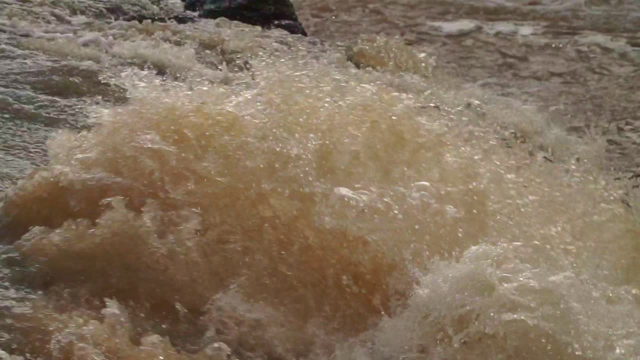 Fast-moving muddy river water crashing and swirling with powerful force. The turbulent currents and earthy tones. natural disasters, floods, extreme weather, or raw nature
