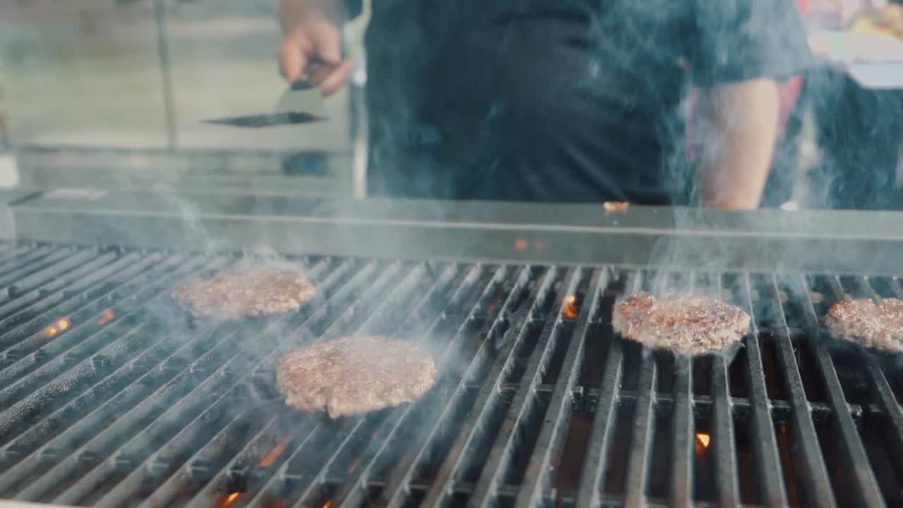 hombre arrojando una hamburguesa a la parrilla provocando una gran llama