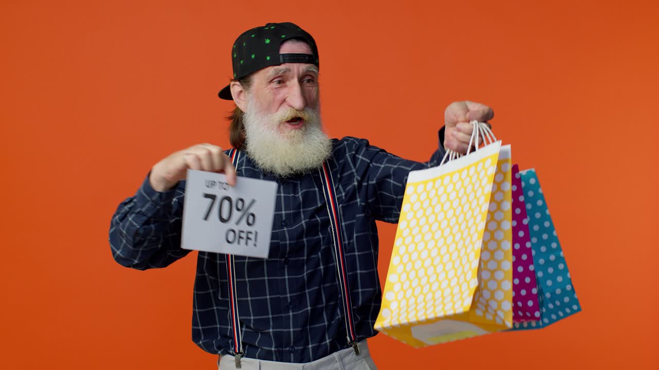 un hombre mayor barbudo mostrando bolsas de compras y hasta un 70 por ciento de descuento en las inscripciones.
