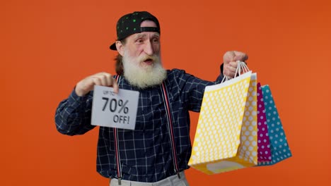 un hombre mayor barbudo mostrando bolsas de compras y hasta un 70 por ciento de descuento en las inscripciones.