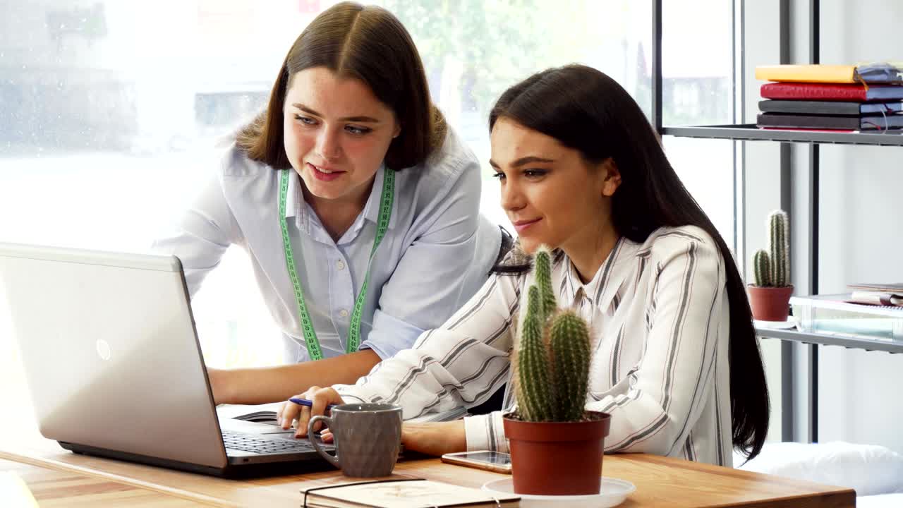 Designer e sua assistente trabalhando juntas no laptop