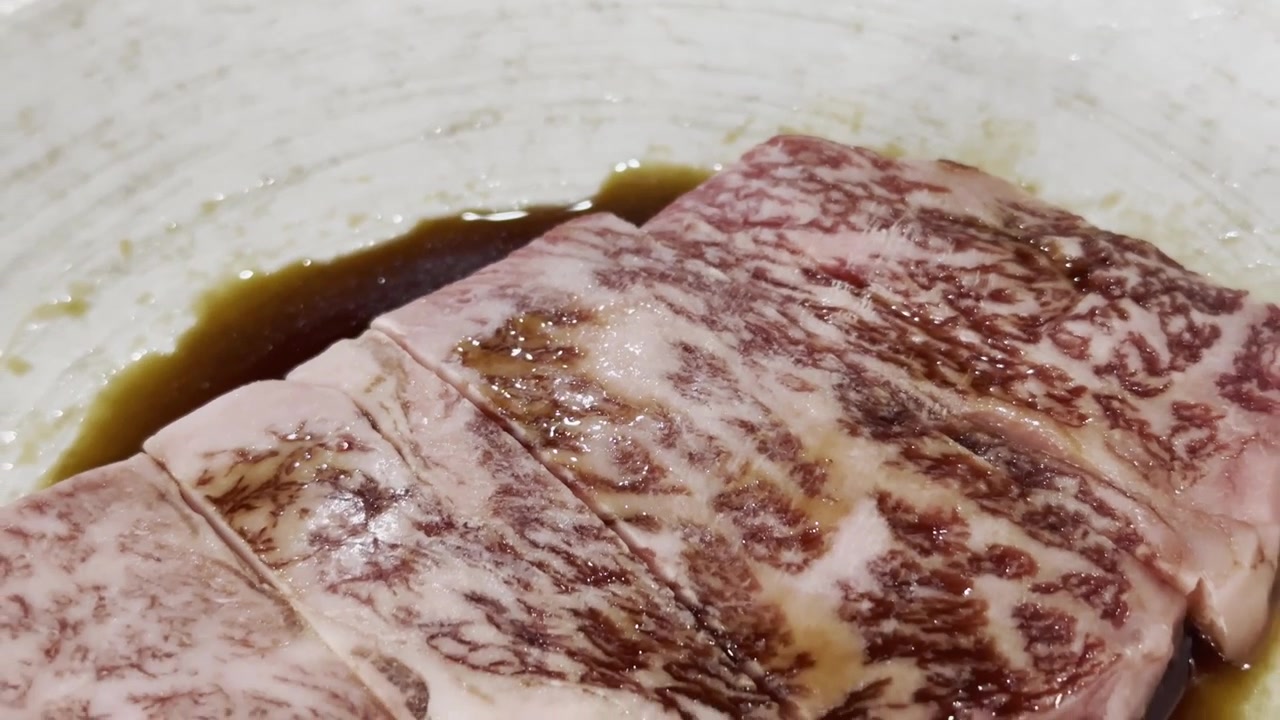Primo piano di fette di pregiato manzo Wagyu A5 disposte su un piatto da portata, che evidenziano una marezzatura eccezionale e una presentazione elegante per la ristorazione gourmet