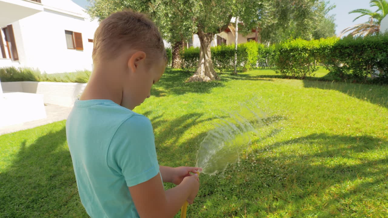 집 근처 에 있는 초록색 잔디 에 물 을 주고 있는 놀이 하는 아이