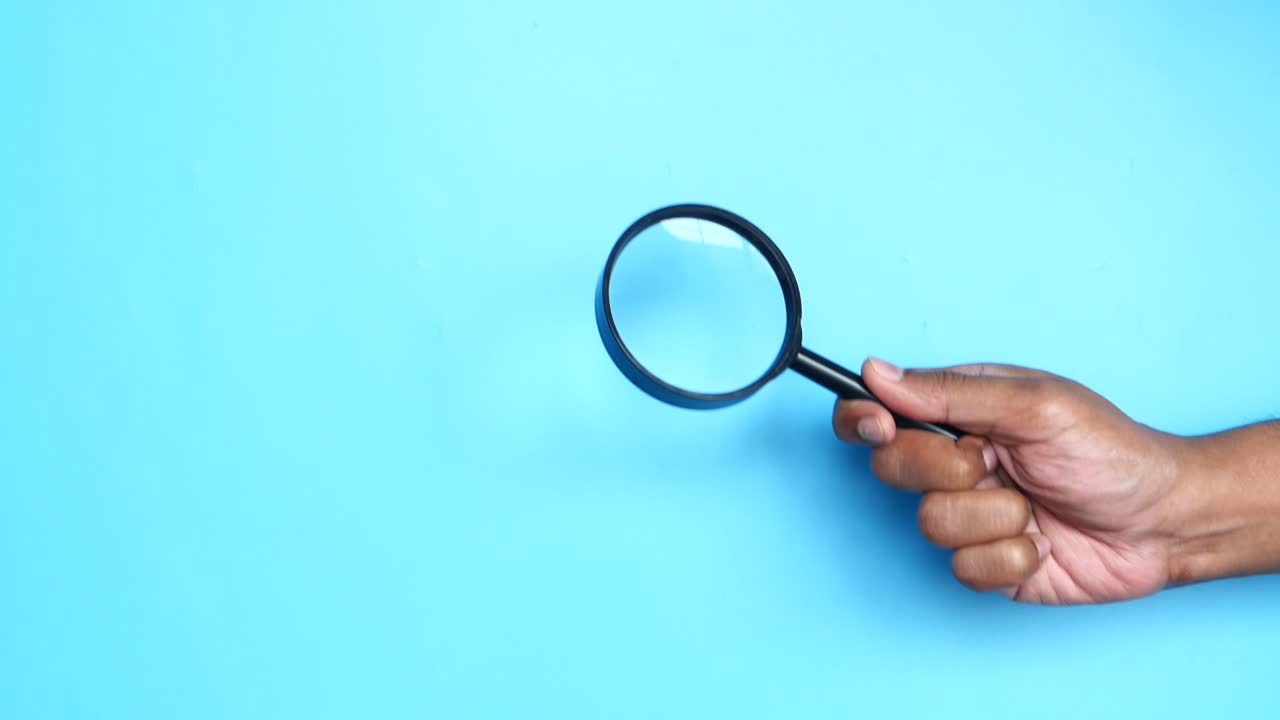 mano sosteniendo una lupa sobre un fondo azul