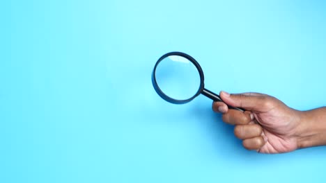 hand holding a magnifying glass on a blue background