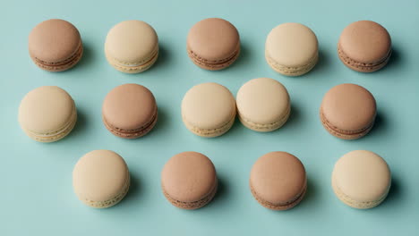 an array of brown and beige macarons on a light blue background