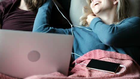 pareja escuchando música mientras usa una computadora portátil en el sofá 4k