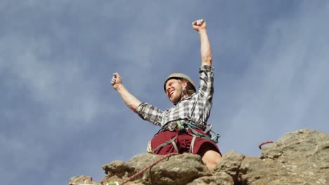 climber cheering after reaching the top of cliff 4k