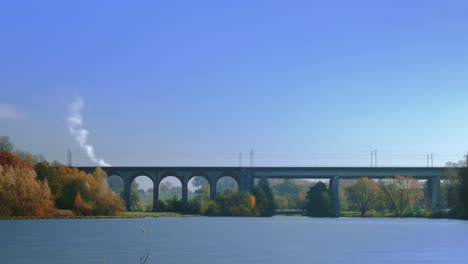 Un-Lapso-De-Tiempo-De-Un-Lago-Y-Un-Puente-Ferroviario-Con-Un-Zoom-Lento