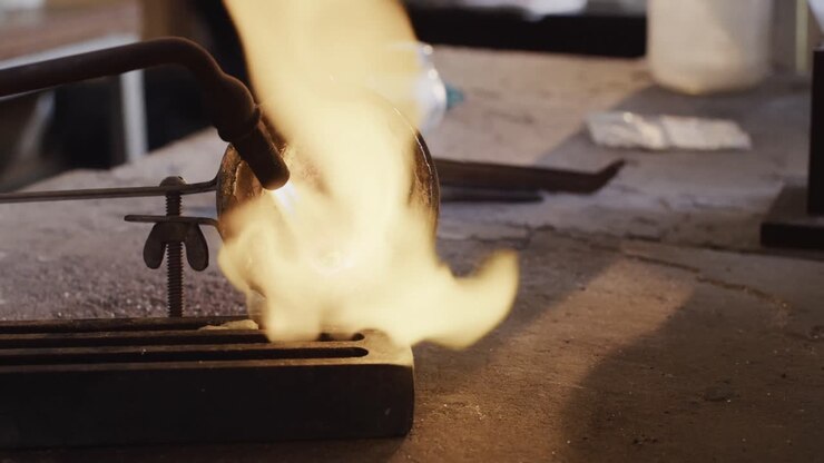 Close up of melting metal with blowtorch in workshop in slow motion