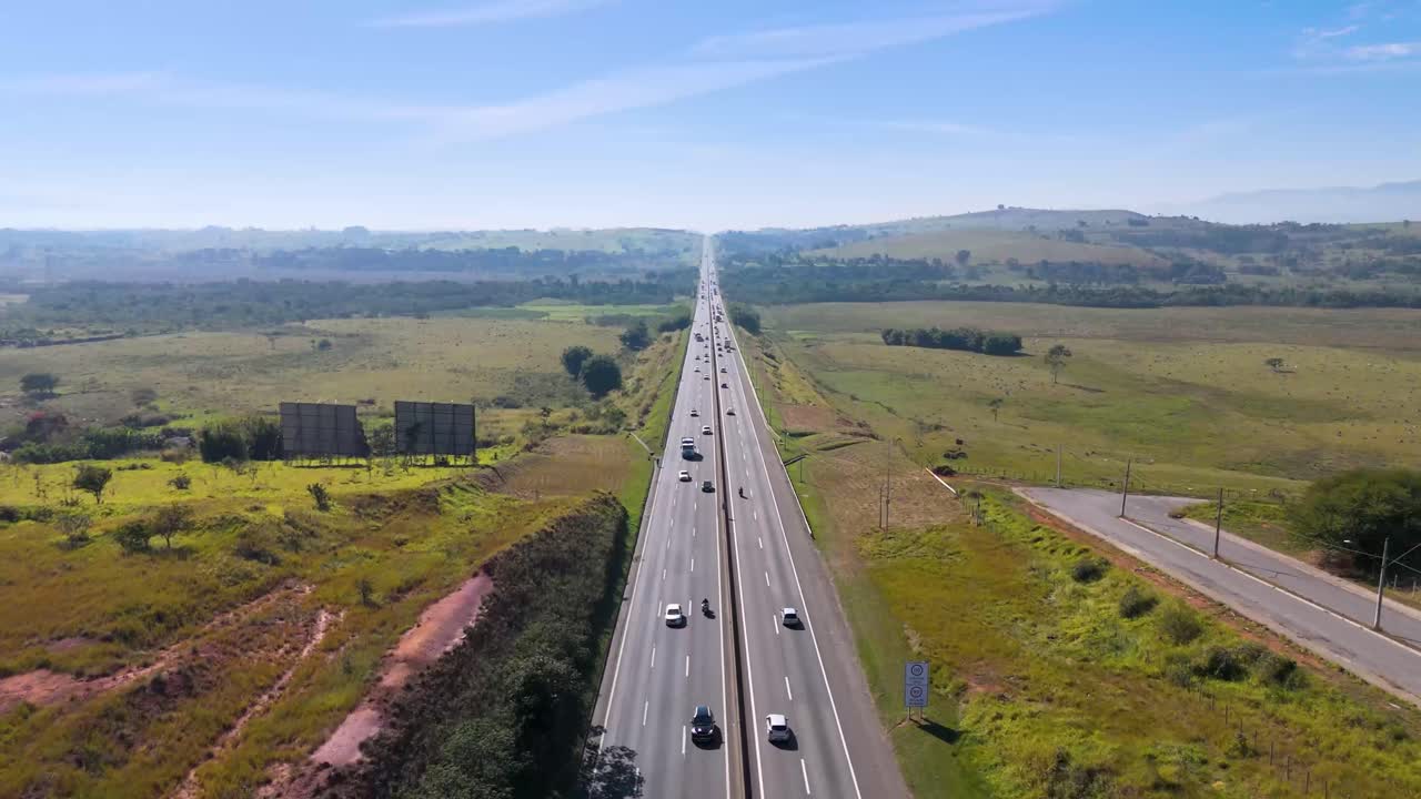 Vista aérea de uma rodovia rural cortando uma paisagem com veículos em movimento - Brasil.