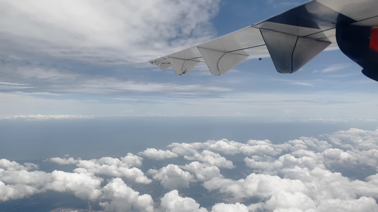 Bird's-eye view from an airplane above a serene island and clouds, capturing the flight's mesmerizing journey through the cloud cover