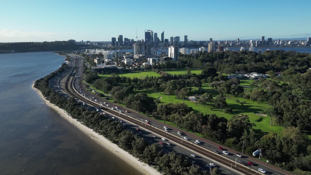 toma aérea del tráfico en la autopista costera y el horizonte de la ciudad de perth en el fondo en un día soleado con cielo azul - toma amplia