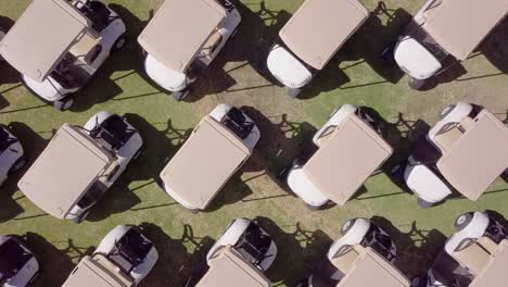 Symmetrical-group-of-golf-carts-or-buggies,-drone-top-down-flyover-medium-shot