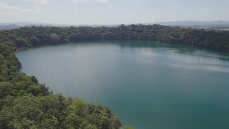 Paisaje-Idílico-En-El-Lago-Eacham-Con-Aguas-Tranquilas-Y-Vegetación-Exuberante-En-La-Meseta-De-Atherton,-Queensland,-Australia---Disparo-De-Drones