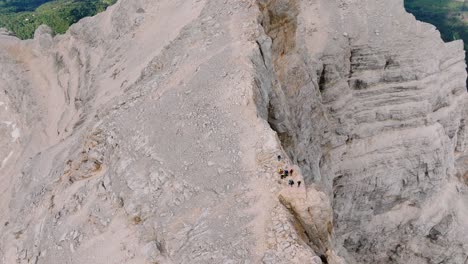 drone top down shot showing group of hikers arriving peak on dangerous edge of mountain