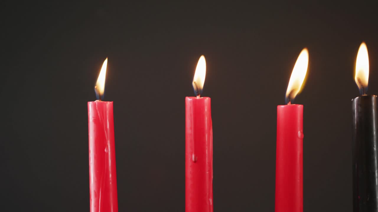 Composizione di candele di Halloween accese verdi, nere e rosse su sfondo nero