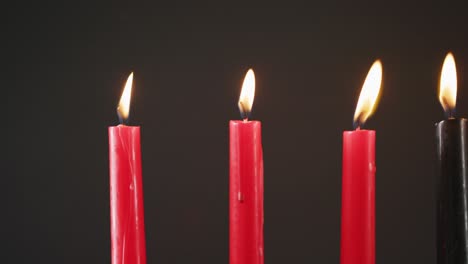 composición de velas verdes, negras y rojas encendidas de halloween contra un fondo negro