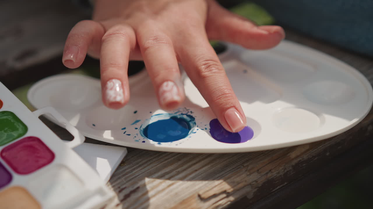 Esplorazione di colori vivaci. Creatività spontanea catturata attraverso un dito nella pittura vibrante. Momento artistico giocoso che coinvolge il contatto del dito con vernici viola e blu brillanti su una superficie di legno.