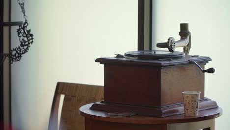 vintage wooden vinyl turntable next to a glass of coffee inside an old house