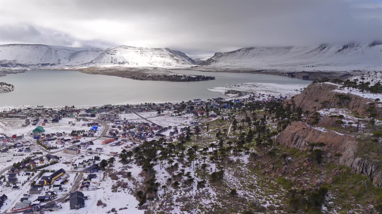 Snowy aerial view of Caviahue town, lake, and surrounding mountains in Neuquén, Patagonia, Argentina